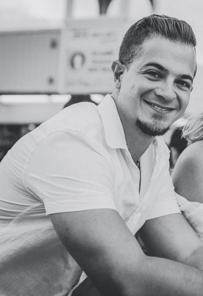 Anthony Fattizzi is leaning to the right, smiling. The entire photo is black and white.
